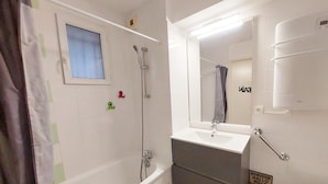 Ein Badezimmer mit einer Badewanne, einem Waschbecken, einem Spiegel und einer Dusche.