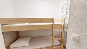 Ein Stockbett in einem Raum mit weißen Wänden und einem gemusterten Wandpapier.