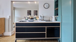 Eine moderne Küche mit Backofen, Spüle und einer Uhr an der Wand.
