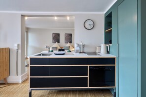 A modern kitchen with a built-in oven, a sink, and a clock on the wall. - Seelicht | Altstadt Refugium | seeglueck (Radolfzell am Bodensee)