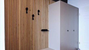 Une pièce avec un mur recouvert de lambris en bois, une armoire blanche et un banc.