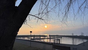 Une vue sur le coucher de soleil au-dessus d’une étendue d’eau calme, avec une jetée qui s’avance dans l’eau.