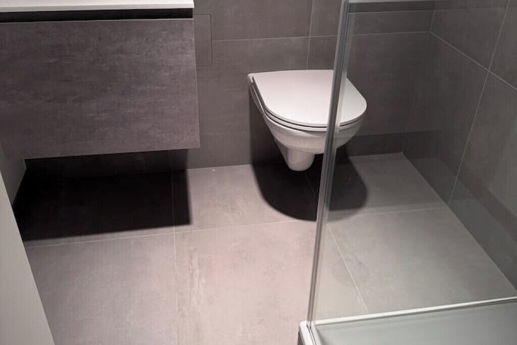 Une salle de bain moderne comprenant des toilettes, un espace douche et un lavabo.