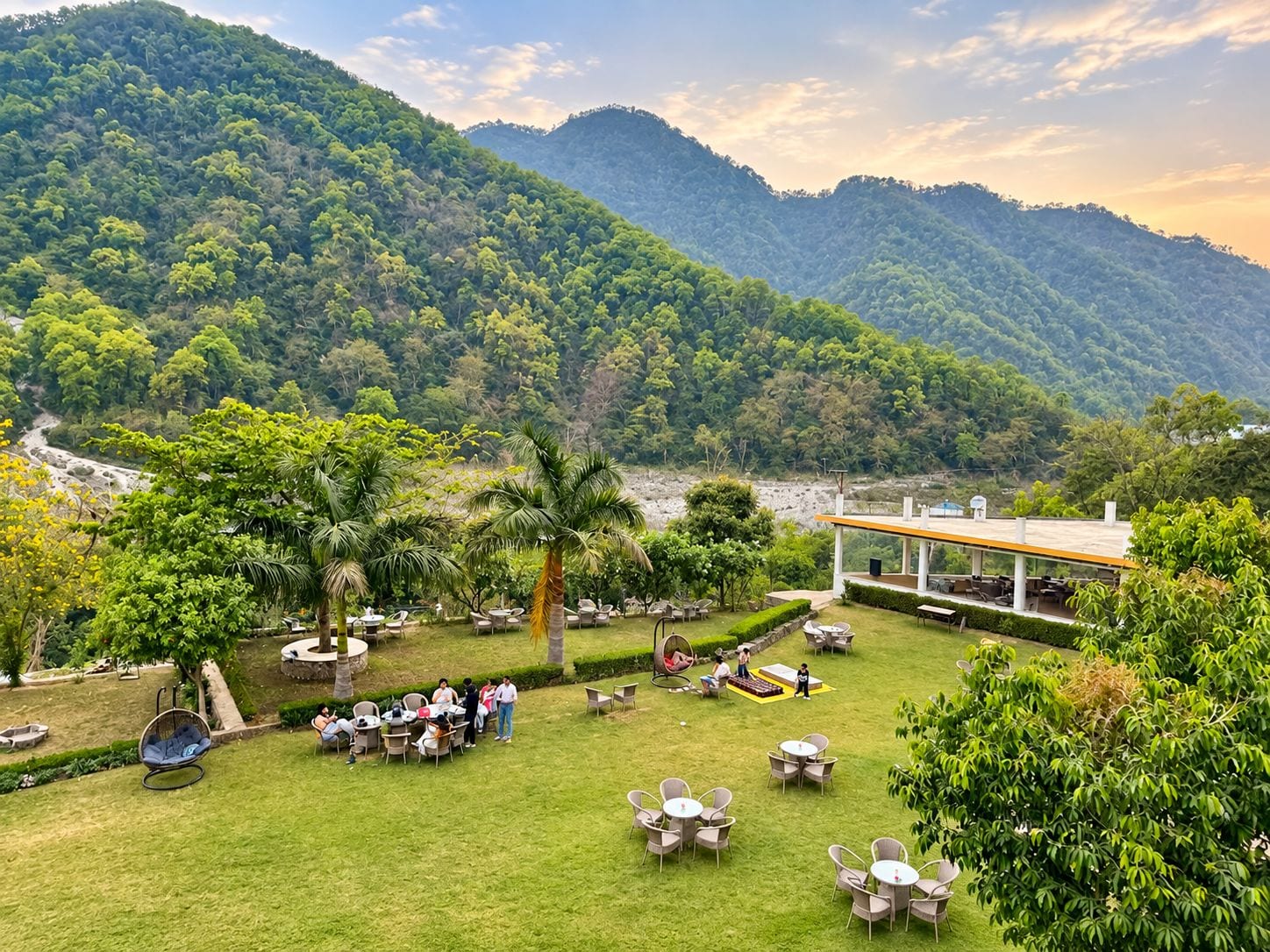 A lush outdoor area with seating arrangements and a view of a mountainous landscape.