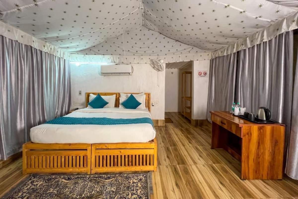 A bedroom with a bed, wooden headboard, a nightstand, a patterned rug, and a ceiling with a star pattern.