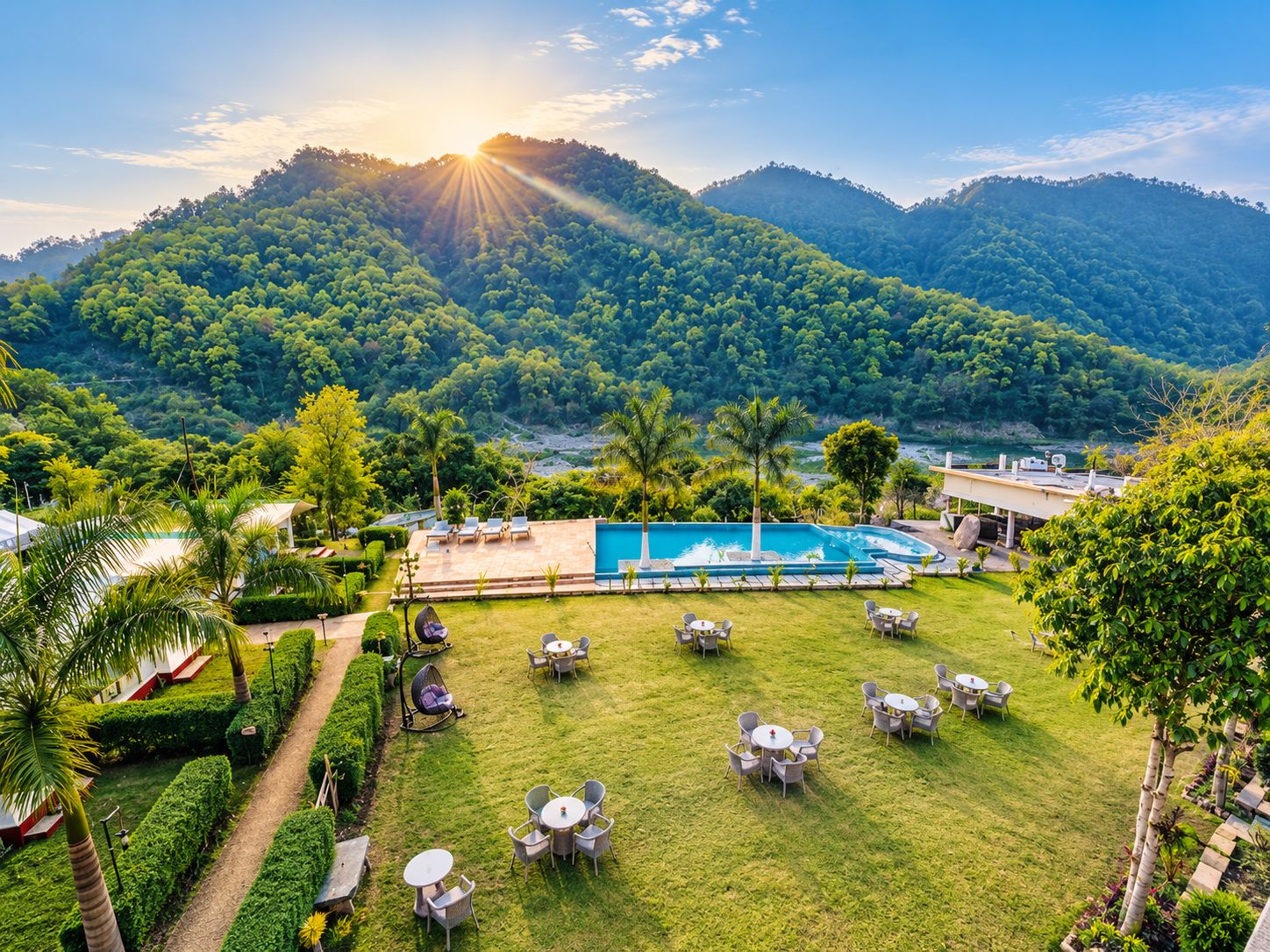 A pool area with multiple seating arrangements and a view of a mountainous landscape.