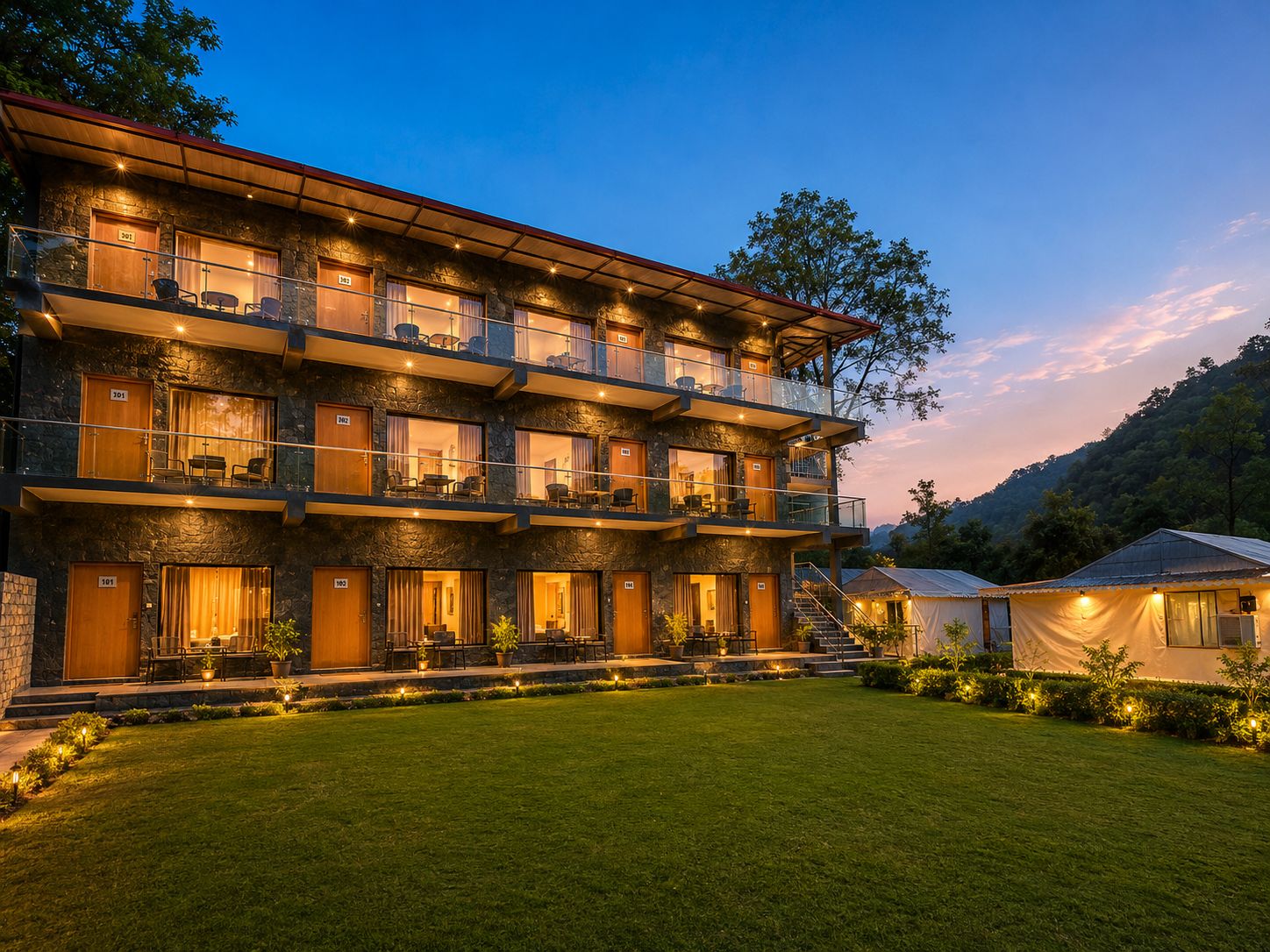 Un hotel de varios pisos con balcones, fachada de piedra y un espacio exterior bien iluminado.