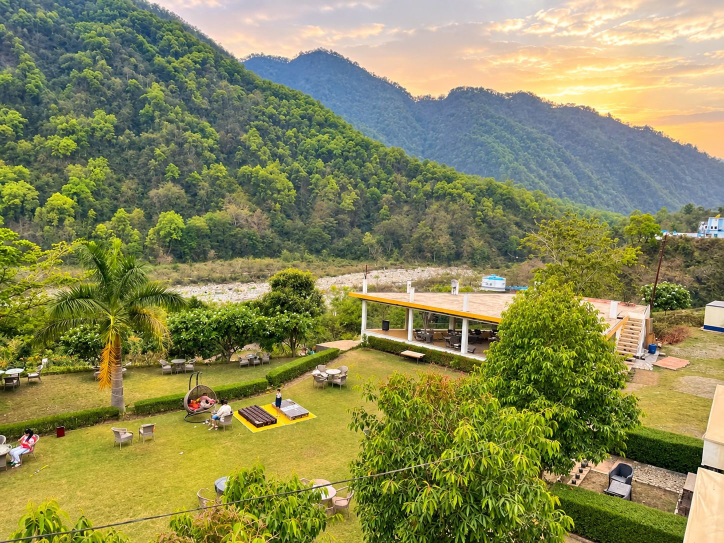 A resort with outdoor seating, a covered area, and a view of a mountainous landscape.