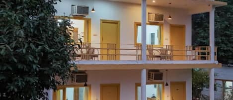 A two-story building with balconies, outdoor seating, and potted plants.