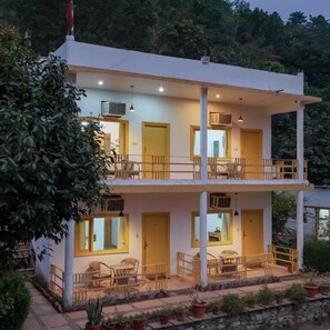 A two-story building with balconies, outdoor seating, and potted plants. - Wild Vista Marchula Riverside Resort Jim Corbett (Marchula)