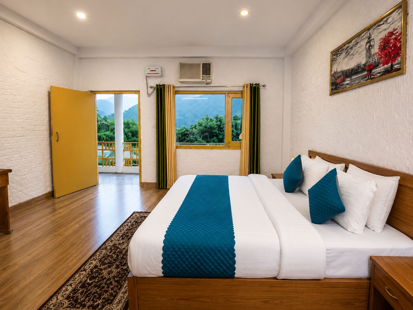A hotel room with a bed, a window with curtains, an air conditioning unit, and a painting on the wall.