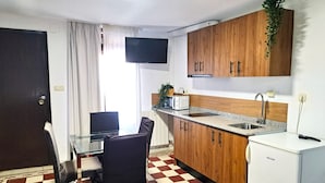 A compact kitchen with wooden cabinets, a white refrigerator, a microwave, a toaster, and a sink. - Casa cubo (Alhama de Granada)