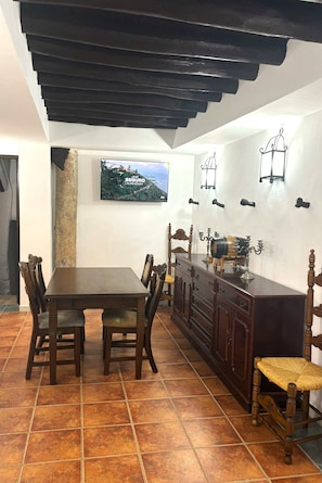 A dining area with a wooden table and chairs, a dark wooden cabinet, and a wall-mounted light fixture.