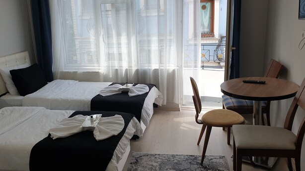 Une chambre d’hôtel avec deux lits, une petite table ronde et une chaise.