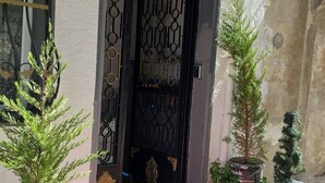 L’entrée d’un hôtel, avec un tapis rouge, un portail noir orné et une enseigne indiquant « TAKSIM Millennium SUIT HOTEL ».