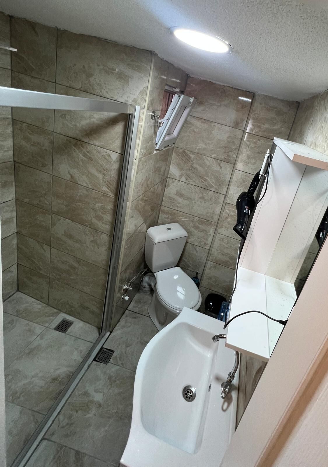 Un bagno con doccia, WC e lavandino.