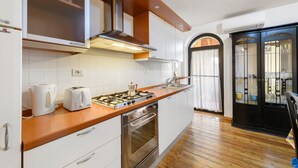 A modern kitchen with a gas stove, toaster, and oven, wooden countertop, white cabinets, and a black cabinet with glass doors. - Apartment 'Luna' with Shared Terrace, Wi-Fi and Air Conditioning (San Felice del Benaco)