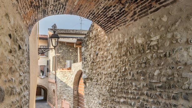A narrow alleyway with stone walls, a wooden door, and a metal gate. - Apartment 'Luna' with Shared Terrace, Wi-Fi and Air Conditioning (San Felice del Benaco)