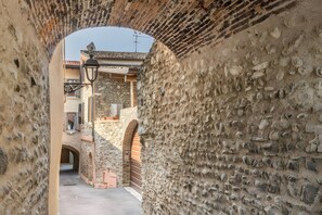 A narrow alleyway with stone walls, a wooden door, and a metal gate. - Apartment 'Luna' with Shared Terrace, Wi-Fi and Air Conditioning (San Felice del Benaco)