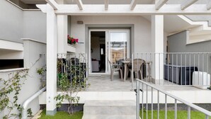 Ein Wohnhaus mit überdachter Terrasse, Sitzgelegenheiten im Freien und einem sichtbaren Hauseingang.