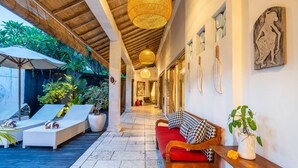 A corridor with a wooden ceiling, a red sofa, and a bench with a potted plant. - Private Pool | Daily Housekeeping | Central Seminyak (Seminyak)