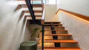 Una escalera moderna con escalones de madera y barandillas de metal, que conduce a un piso superior.
