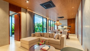A modern living room with a sectional sofa, a coffee table, and a dining area with a kitchen in the background. - Modern Villa | Private Pool | Near Canggu Beach (Kerobokan)