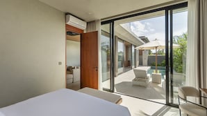 A modern hotel room with a large bed, a balcony with outdoor seating, and a view of the ocean. - Modern Villa | Private Pool | Near Canggu Beach (Kerobokan)