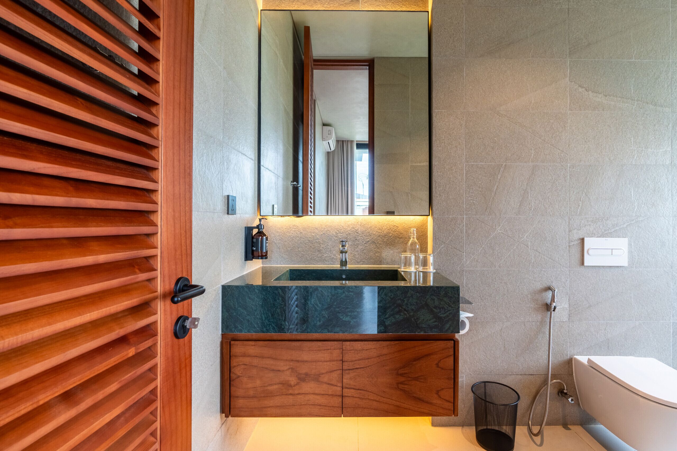 Ein modernes Badezimmer mit einem hölzernen Waschtisch, einem großen Spiegel und einer Dusche.