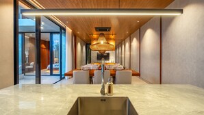 Eine moderne Küche mit einer großen Kochinsel, einer integrierten Spüle und einem Essbereich mit Holztisch und Stühlen.