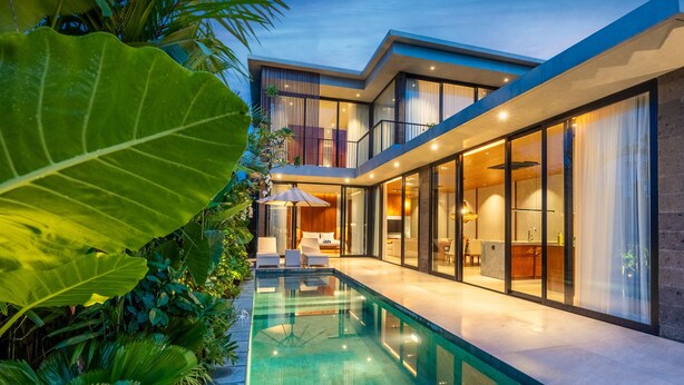Une maison moderne dotée d’une piscine, de grandes fenêtres et d’un intérieur bien éclairé.
