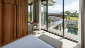 Une chambre moderne avec un grand lit, un bureau et une vue sur une piscine et un espace verdoyant.
