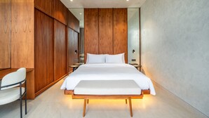 Ein modernes Schlafzimmer mit einem großen Bett, Holzwandverkleidung, einem Nachttisch und einem Sessel.