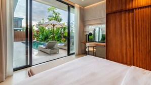 Camera d'hotel moderna con un ampio letto, una scrivania e vista su una piscina all'aperto.