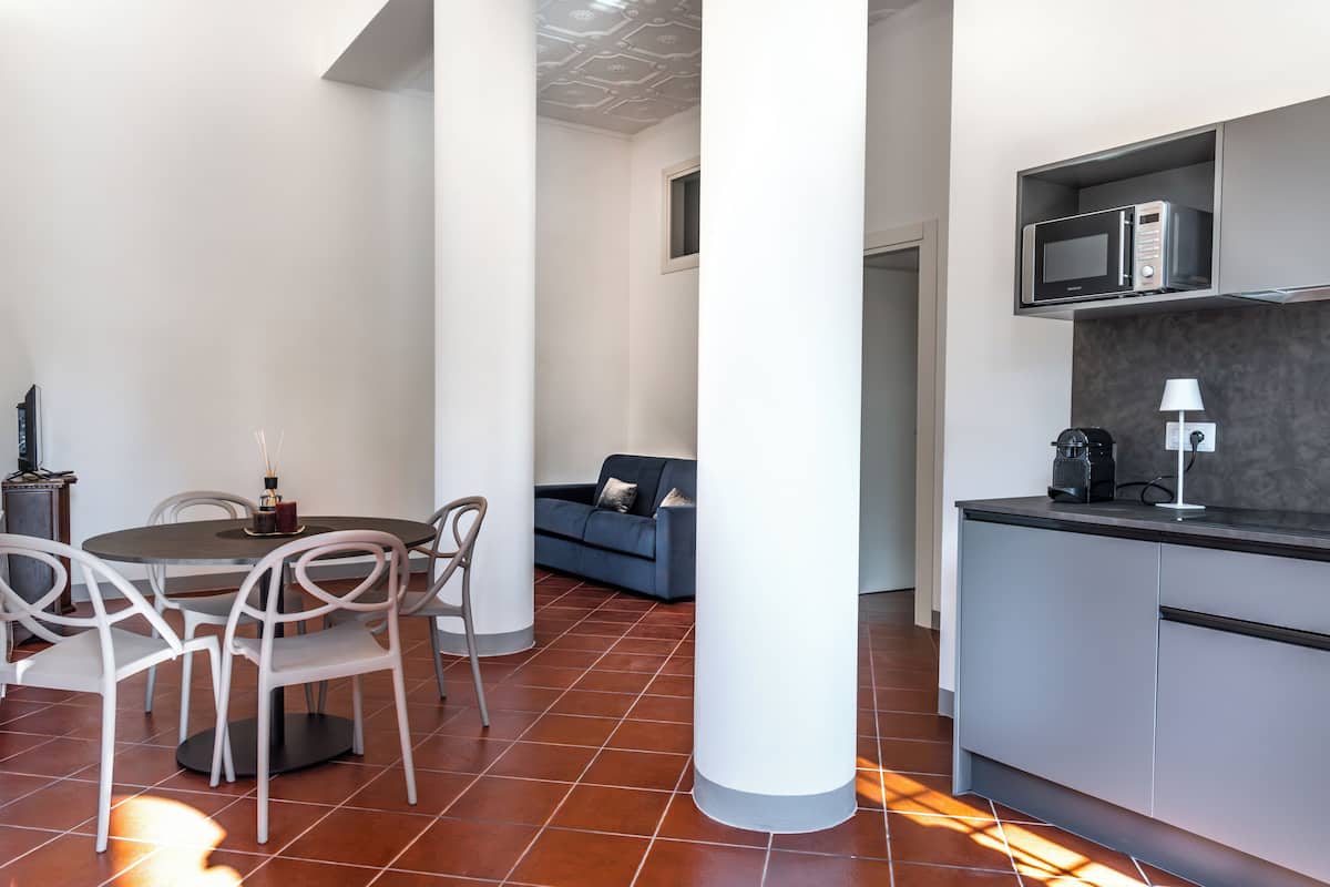 A modern living space with a dining area, a sofa, and a kitchen with a microwave.