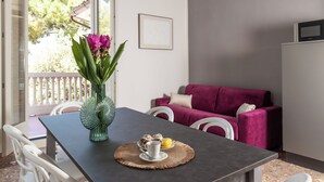 A dining area with a table set for two, a vase with flowers, and a view of a balcony with a railing. - Villa Leda (Porto Recanati)