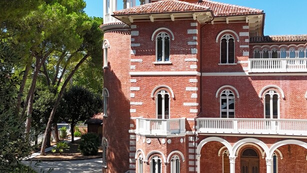 A large, red-brick building with a central tower, arched windows, and a covered walkway. - Villa Leda (Porto Recanati)