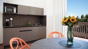 A modern kitchen with a microwave, sink, and orange chairs. - Villa Leda (Porto Recanati)