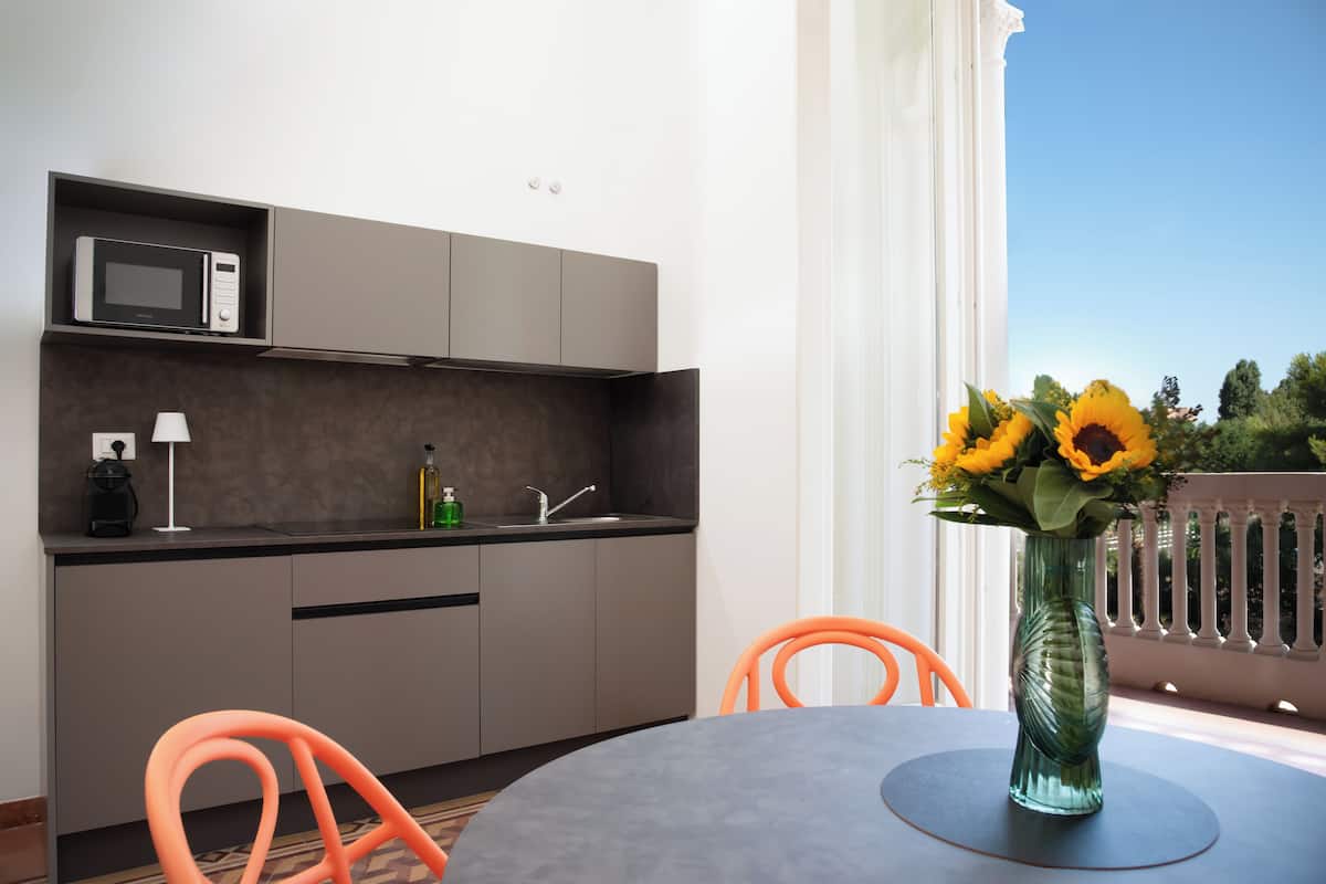 A modern kitchen with a microwave, sink, and orange chairs.
