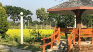 A gazebo with a thatched roof, wooden railings, and a stone base. - Hotel Rowshon Int Jamalpur (Jamalpur)