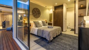 Een moderne slaapkamer met een groot bed, een glazen schuifdeur naar een balkon en een ronde decoratie aan de wand.