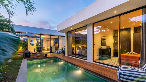 Een modern huis met een zwembad, grote glasramen en een gezellig terras.