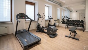 Een sportschool met loopbanden, elliptische trainers en een bank.