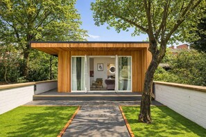 Ein modernes Haus mit Holzfassade, einem Glastür-Eingang und einem sichtbaren Wohnbereich mit Möbeln.