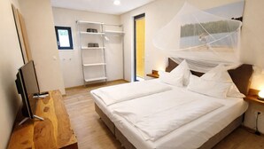 Ein Schlafzimmer mit Bett, Nachttischen, einem Fernseher, einem Kleiderschrank und einem Fenster mit Seeblick.