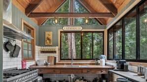 Cocina rústica de granja con vigas de madera, un ventanal grande y un letrero que dice "FARMHOUSE".