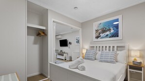 A bedroom with a bed, a bedside table, a nightstand, a TV, and a painting on the wall. - Bright 1-Bed Apartment in Fortitude Valley (Fortitude Valley)