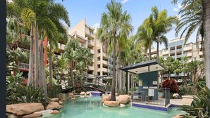 A resort pool with a bridge, palm trees, and a building with balconies. - Bright 1-Bed Apartment in Fortitude Valley (Fortitude Valley)