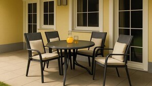 A patio with a round table and six chairs, surrounded by large windows. - Stylish mountain apartment with terrace in Flattach near Mölltal Glacier (Flattach)