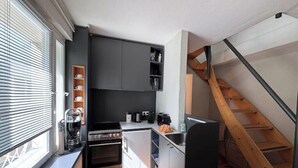 A compact kitchen with a built-in oven, a coffee machine, and a sink. - Small house | city location | seeglueck (Konstanz)